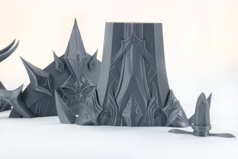 Puede incluir: Un conjunto de piezas de pl&aacute;stico gris impresas en 3D con dise&ntilde;os intrincados. Las piezas tienen forma de corona, torre y una peque&ntilde;a aguja.
