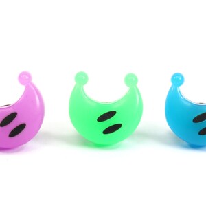 May include: Three crescent moon shaped plastic finger puppets in purple, green, and blue with black eyes.