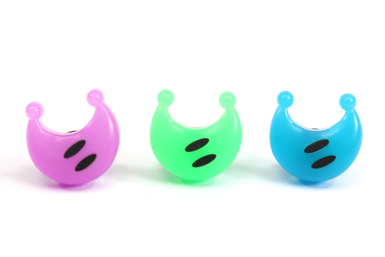 May include: Three crescent moon shaped plastic finger puppets in purple, green, and blue with black eyes.