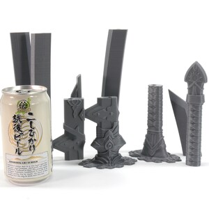May include: A set of seven grey 3D printed sword parts, including a hilt, blade, and pommel. The parts are arranged on a white surface next to a can of Japanese beer.