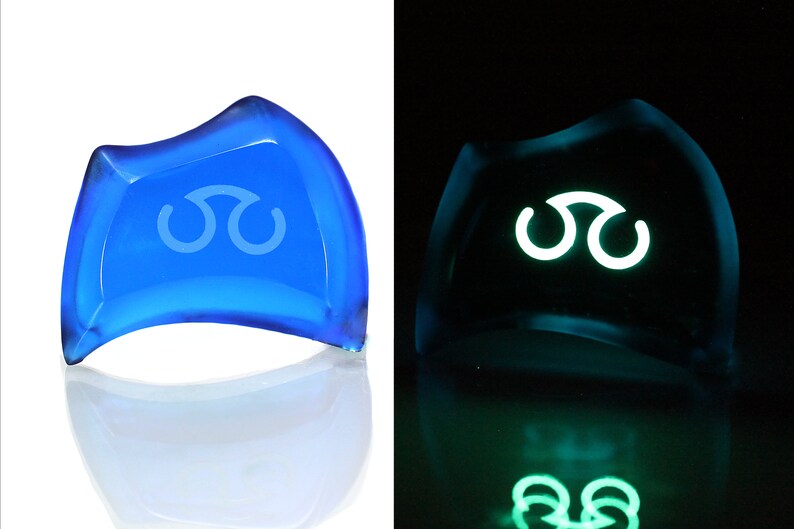 May include: A blue glass paperweight with a white symbol, glowing green in the dark.