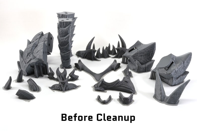 May include: A set of 14 gray 3D printed plastic pieces for a model kit. The pieces are in various shapes and sizes, including spikes, horns, and a tall, segmented tower. The pieces are arranged on a white surface. The text "Before Cleanup" is visible at the bottom of the image.