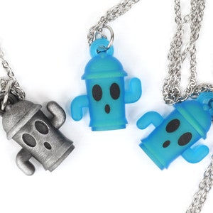 May include: Three silver chain necklaces with a blue and silver cactus pendant. The cactus pendant has a cartoon face with two eyes and a mouth.