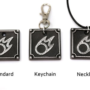 May include: Three versions of a silver metal charm featuring a stylized fire symbol on a black background. The charm is available as a standard charm, a keychain, and a necklace.