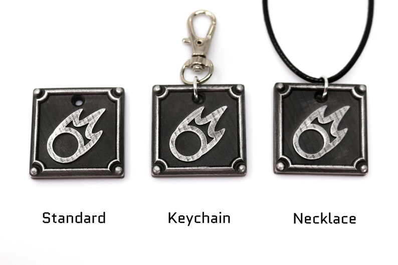 May include: Three versions of a silver metal charm featuring a stylized fire symbol on a black background. The charm is available as a standard charm, a keychain, and a necklace.