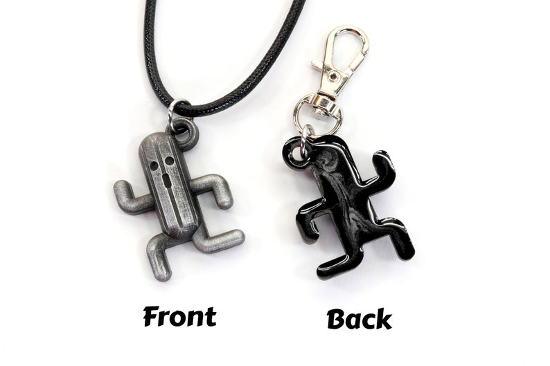 May include: A silver and black charm necklace featuring a running character from the video game Final Fantasy. The charm is shown from the front and back.