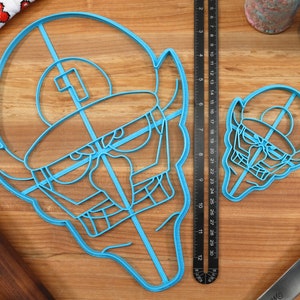 May include: Two blue plastic cookie cutters shaped like a cartoon character with a hat. The larger cutter is about 12 inches wide and the smaller cutter is about 6 inches wide.