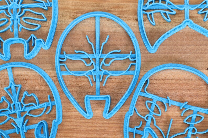 K&ouml;nnte beinhalten: Satz von f&uuml;nf blauen Plastik-Ausstechern, jeder mit einem anderen Design. Die Ausstecher liegen auf einer Holzoberfl&auml;che.