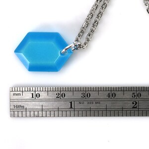 May include: A light blue hexagonal pendant necklace with a silver chain. The pendant is approximately 2 cm wide.