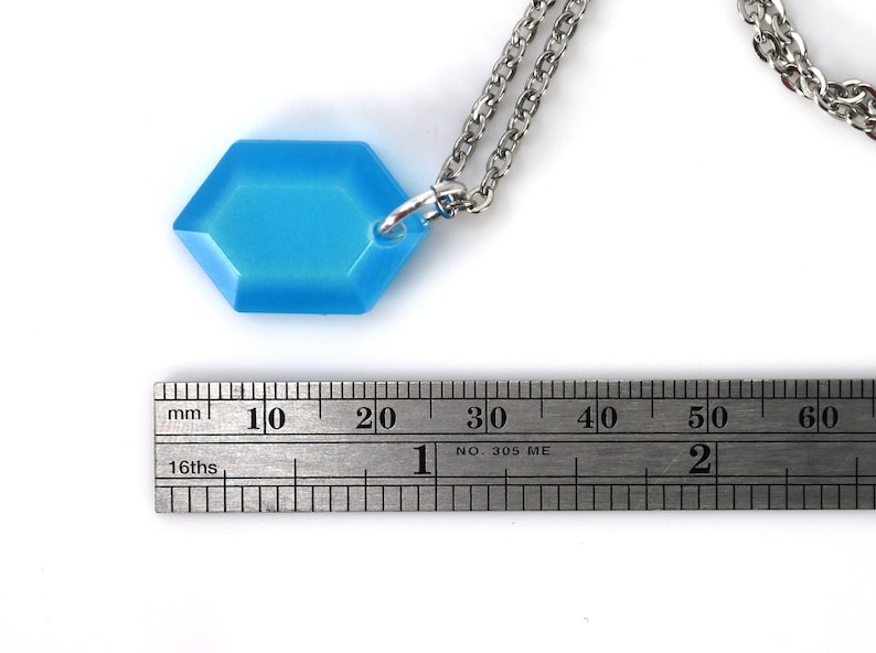May include: A light blue hexagonal pendant necklace with a silver chain. The pendant is approximately 2 cm wide.