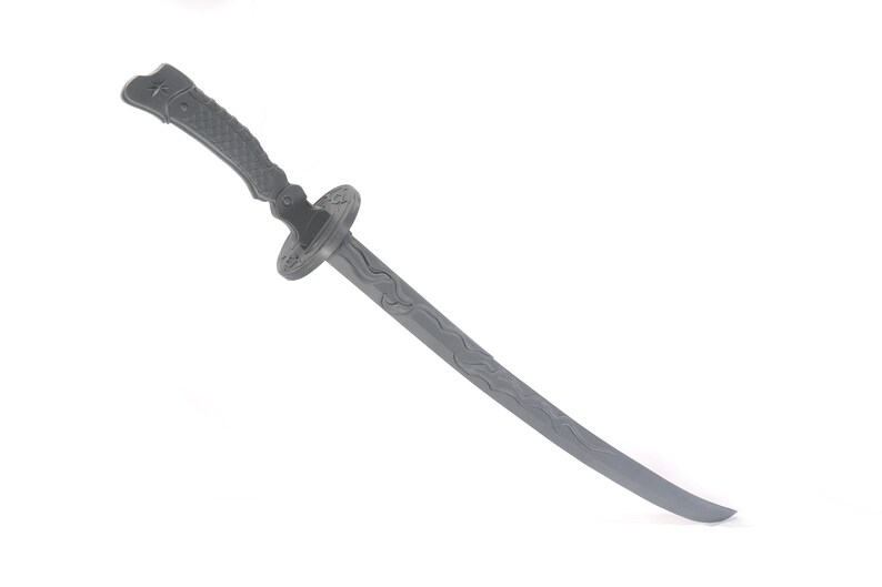 Może przedstawiać: Szary, plastikowy miecz katana. Rękojeść ma teksturowany uchwyt, a osłona jest okrągła z dekoracyjnym wzorem. Ostrze ma zakrzywioną krawędź i falisty wz&oacute;r. Zabawka ma przypominać tradycyjny japoński miecz.