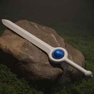 May include: A white sword with a blue gem in the handle, resting on a rock covered in green moss.