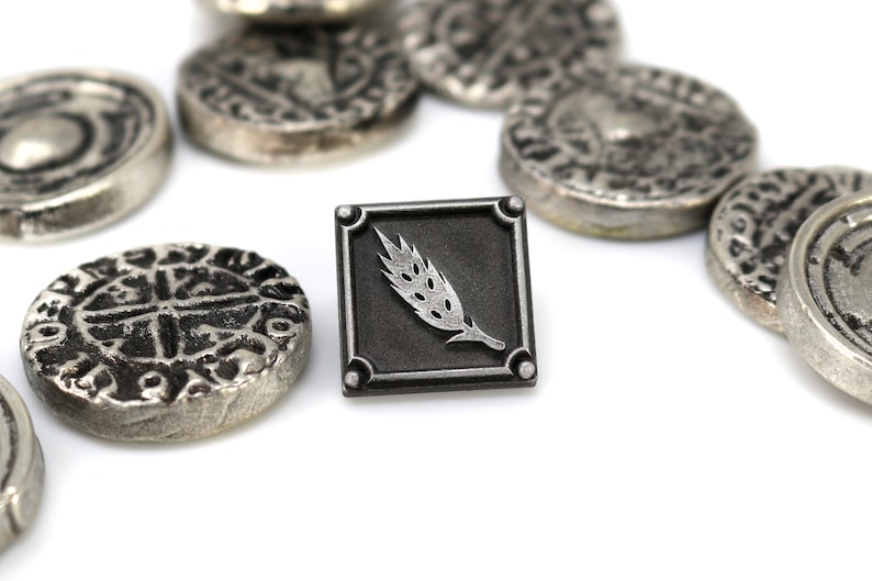 May include: A silver metal pin with a black square background and a silver wheat stalk design.