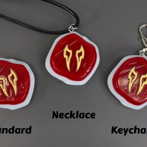May include: Three versions of a red and gold charm with a stylised flame design. The charm is available as a necklace, keychain, and standard charm.