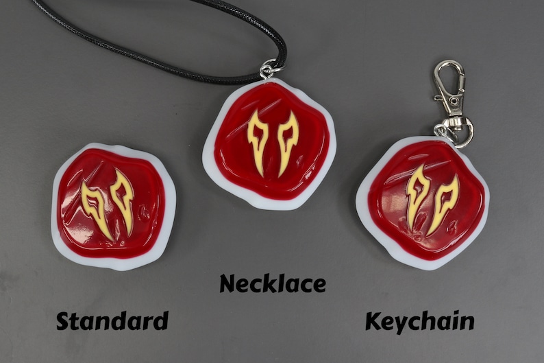 May include: Three versions of a red and gold charm with a stylised flame design. The charm is available as a necklace, keychain, and standard charm.