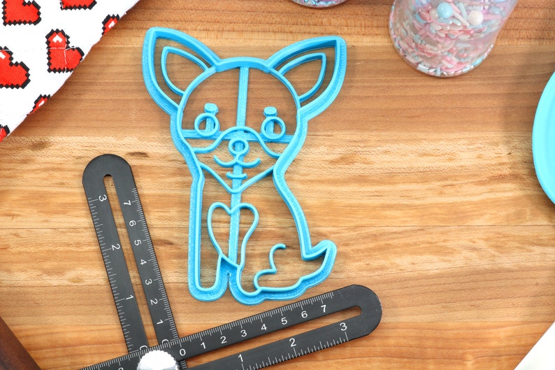 Puede incluir: Un cortador de galletas de pl&aacute;stico azul claro con forma de chihuahua con un coraz&oacute;n en el pecho.