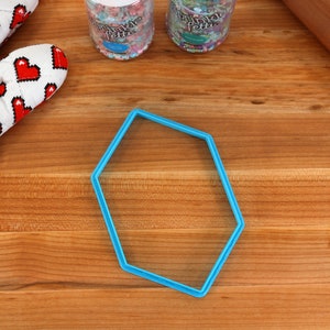 Op de afbeelding: Een blauwe, zeshoekige koekjesuitsteker van plastic op een houten oppervlak.