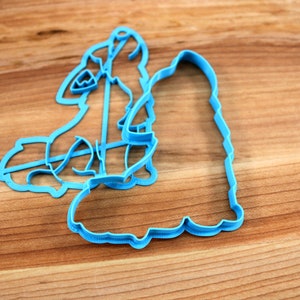 May include: A blue plastic cookie cutter shaped like a snowman with a hat and scarf.