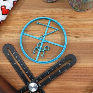 May include: A blue plastic cookie cutter shaped like a stick figure doing a handstand. The cookie cutter is on a wooden surface.