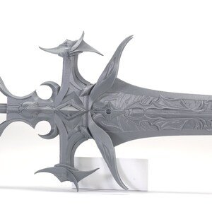 Puede incluir: Una espada gris de dise&ntilde;o intrincado con una punta afilada y una empu&ntilde;adura decorativa. La espada est&aacute; hecha de un material liso y texturizado y tiene un dise&ntilde;o detallado.