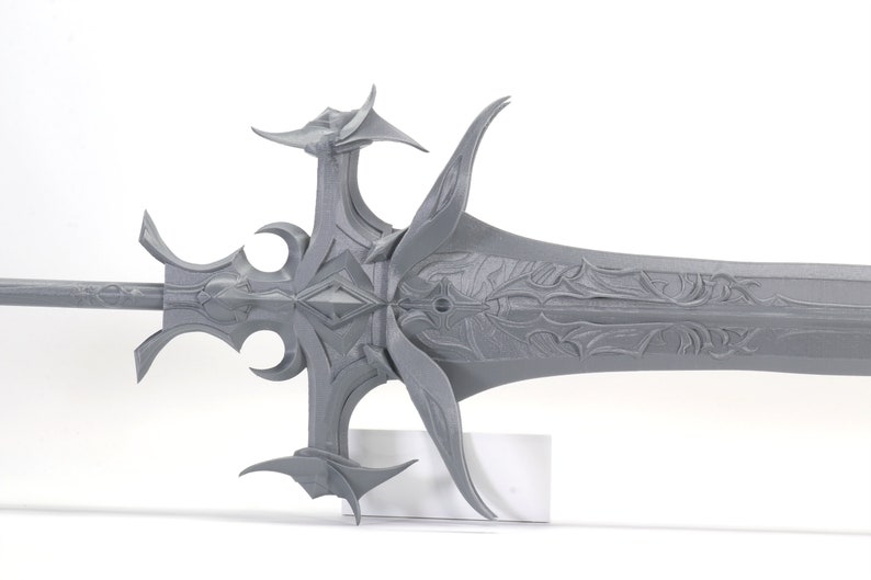 Puede incluir: Una espada gris de dise&ntilde;o intrincado con una punta afilada y una empu&ntilde;adura decorativa. La espada est&aacute; hecha de un material liso y texturizado y tiene un dise&ntilde;o detallado.