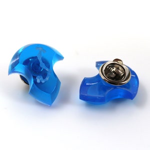 May include: Two blue plastic pinback buttons with a silver metal pinback. The buttons are shaped like a crescent moon.