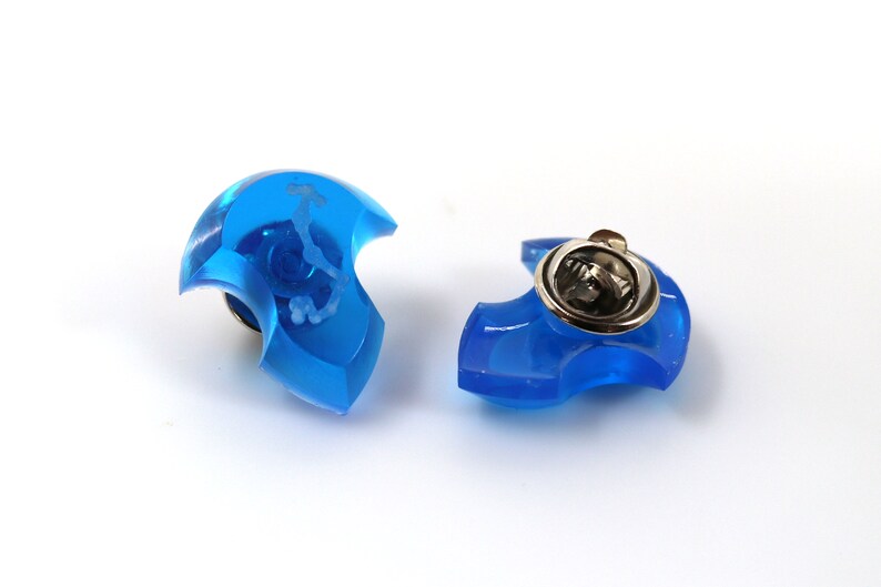 May include: Two blue plastic pinback buttons with a silver metal pinback. The buttons are shaped like a crescent moon.