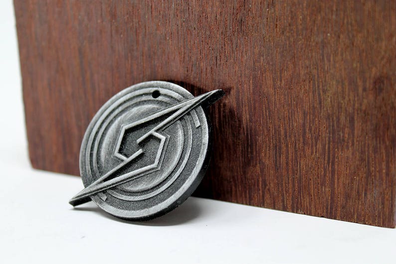 May include: A silver metal pendant with a geometric design. The pendant features a stylized lightning bolt shape within a circular frame.