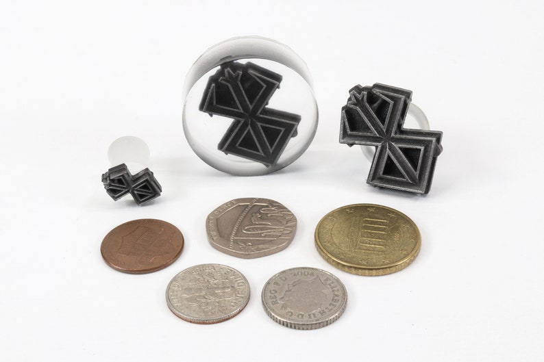 May include: A set of four black metal stamps with a geometric design. The stamps are different sizes and are displayed on a white surface with coins.