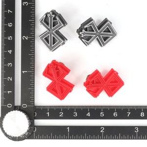 May include: Four small, 3D printed, geometric shapes. Two are silver and two are red. The shapes are all the same design, which resembles a stylized cross.