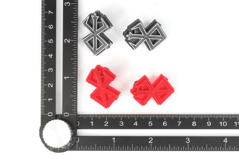 May include: Four small, 3D printed, geometric shapes. Two are silver and two are red. The shapes are all the same design, which resembles a stylized cross.