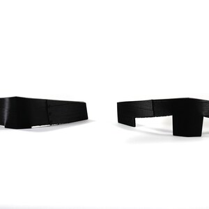 May include: Two black satin bow ties, one with a straight edge and the other with a curved edge.