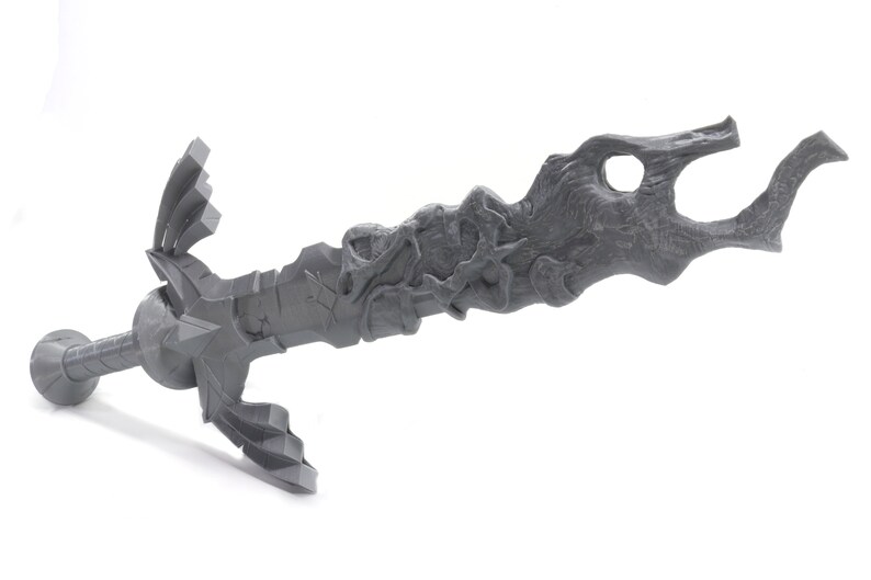 May include: A gray 3D printed sword with a detailed, organic design. The blade is curved and has a textured surface. The hilt is also detailed and has a sharp point.