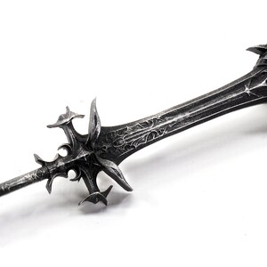 May include: A silver-colored sword with a detailed, ornate design. The sword has a sharp point and a double-edged blade. The hilt is decorated with intricate carvings.