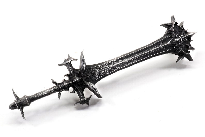 May include: A silver-colored sword with a detailed, ornate design. The sword has a sharp point and a double-edged blade. The hilt is decorated with intricate carvings.