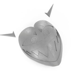 May include: A silver heart-shaped mask with a toothy grin, two eyes, and two small points on top.