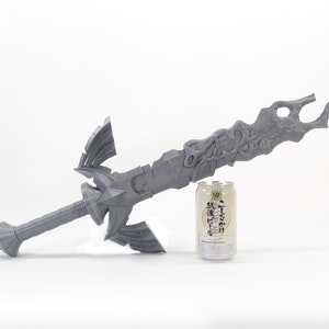 May include: A gray 3D printed sword with intricate details, next to a can of Japanese beer for scale.