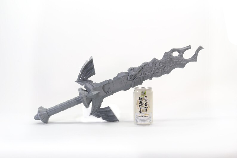May include: A gray 3D printed sword with intricate details, next to a can of Japanese beer for scale.