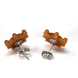 May include: A pair of gold-toned star-shaped earrings with silver posts and backs.