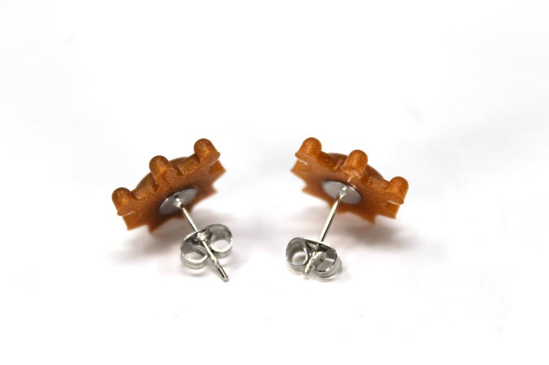 May include: A pair of gold-toned star-shaped earrings with silver posts and backs.