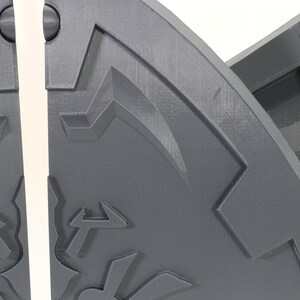 May include: Close-up of a gray, 3D printed, segmented, circular object with a textured surface and a geometric design. The object is split into two sections.