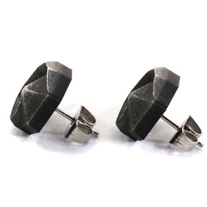 May include: A pair of black geometric stud earrings with silver posts and backs.