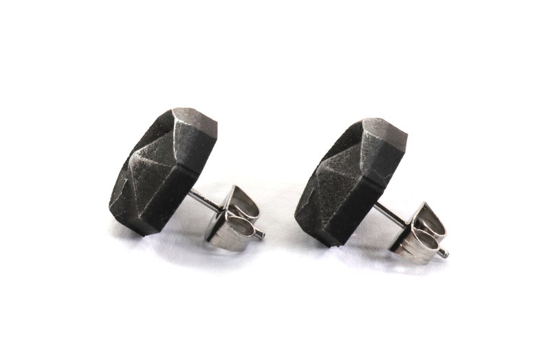 May include: A pair of black geometric stud earrings with silver posts and backs.