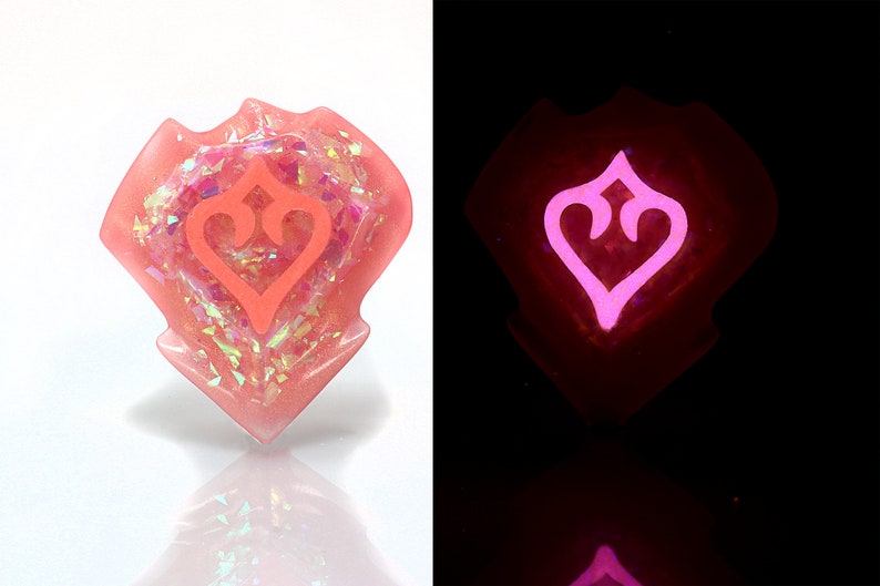 May include: A pink resin heart-shaped charm with a pink heart design inside. The charm glows in the dark.
