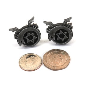 May include: A pair of silver cufflinks featuring the alchemical symbol for the philosopher's stone, a circle with a six-pointed star inside. The cufflinks are about the size of a US dime.