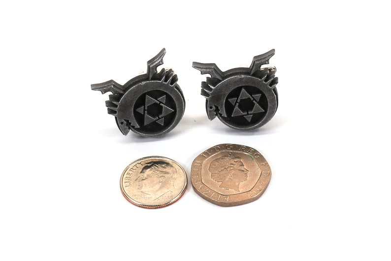 May include: A pair of silver cufflinks featuring the alchemical symbol for the philosopher's stone, a circle with a six-pointed star inside. The cufflinks are about the size of a US dime.
