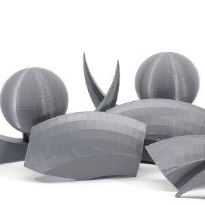 May include: A set of gray 3D printed geometric shapes, including spheres and curved pieces. The shapes are arranged in a cluster on a white background.