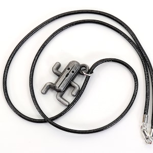 May include: A silver-colored pendant necklace featuring a stylized character from a popular video game. The pendant is attached to a black cord.