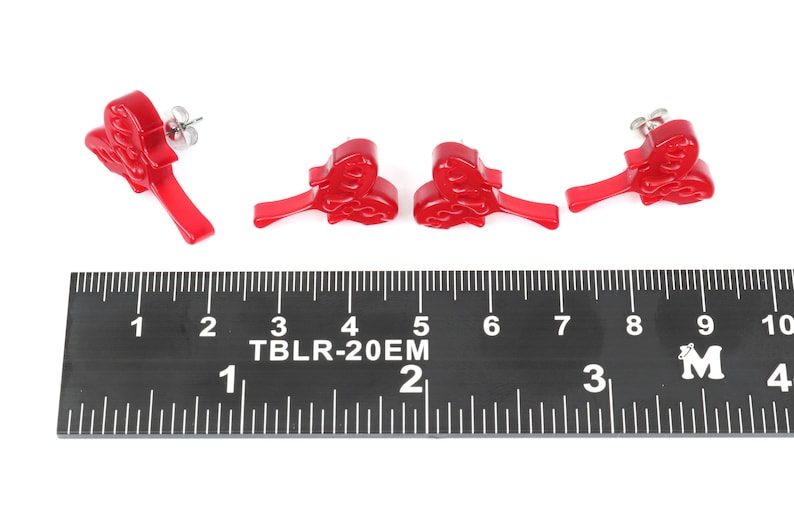 May include: Four red plastic earrings shaped like a heart with a swirl design. The earrings are about 1 inch long and are shown next to a ruler.