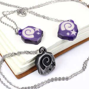 May include: Two silver necklaces with purple and silver pendants featuring a spiral design and white stars.